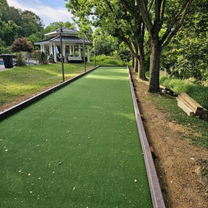 A bocce ball court with artificial turf and a gazebo in the background, lined with trees Maryland