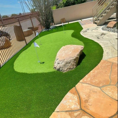 A putting green made of artificial turf with stone accents and small flags.