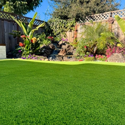 Lush artificial grass with a waterfall and plants.