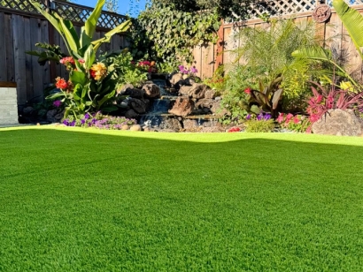 Lush artificial grass with a waterfall and plants.