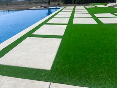 Concrete pavers and artificial grass by a pool.