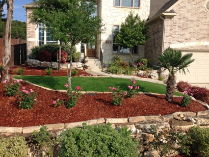 Front Yard with mulch, roses, palm tree, natural stone borders, brick house, decorative bushes