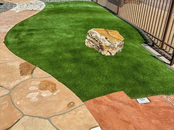 A garden area with artificial turf, large rocks, and a stone walkway.