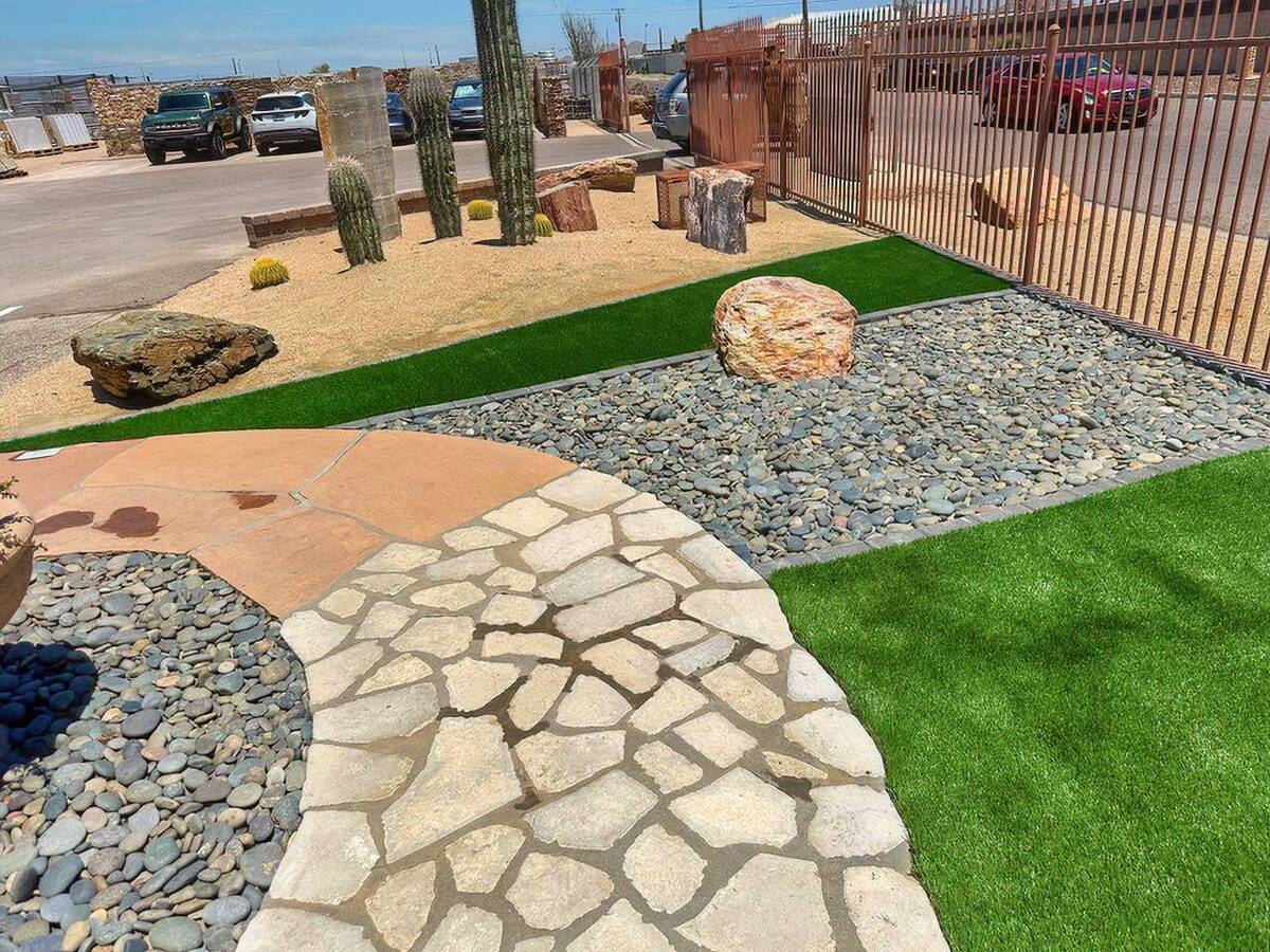A landscaped area featuring artificial turf, stone pathways, and various cacti.